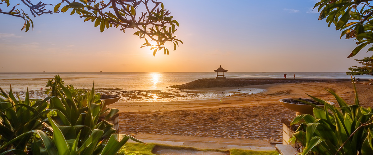 Die Luftaufnahme zeigt die Küste von Gili Trawangan mit türkisfarbenem Wasser und grüner Inselkulisse. Die autofreie Insel vermittelt eine ruhige, entspannte Atmosphäre.